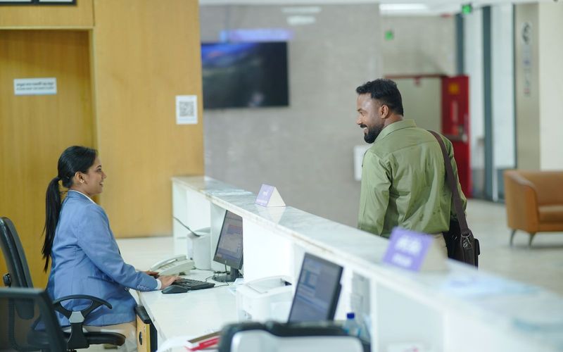 A receptionist assists a guest at the reception desk in a modern hotel lobby in Dhaka, Bangladesh