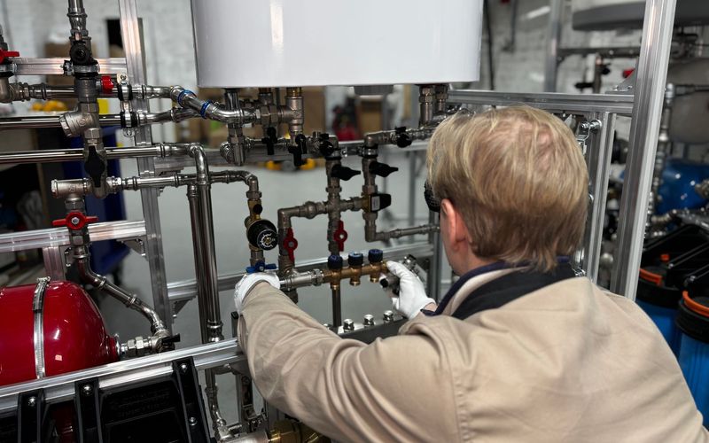 Engineer working on industrial pipe system in a factory for heating and production adjustment